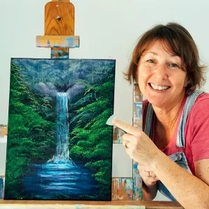 Jenny Buchanan holding fan brush and standing near waterfall tutorial painting